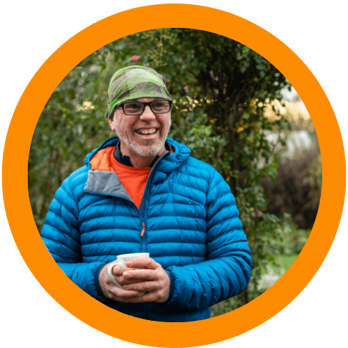 A man holding a cup of tea in his garden
