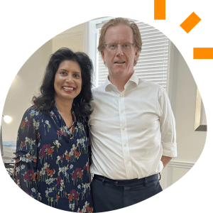 Almona, a woman of colour in her 50s, stands next to Stuart, a white man in his 60s 