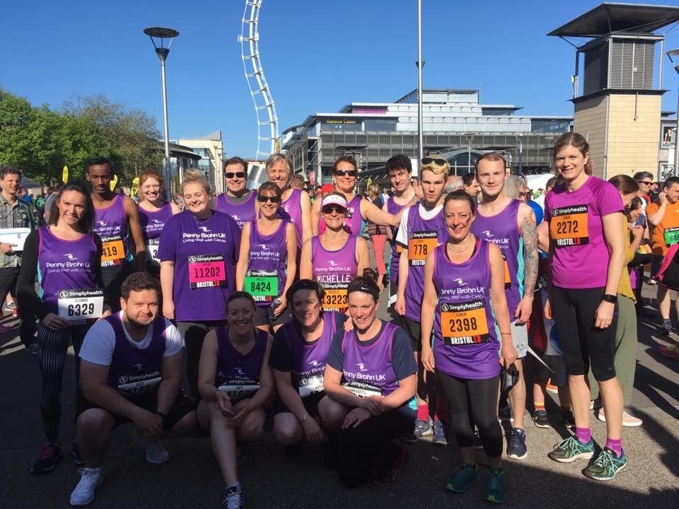 Group of individuals, mix of ages, genders and ethnicity's, all wearing purple vest tops and t-shirts with the Penny Brohn UK logo on the front.