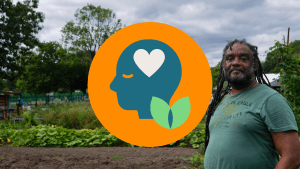 A photo of a black man with long dreadlocks and a grey beard standing in an allotment. Over the top is our 'Your Mind Matters' graphic which is an orange circle with a blue head illustration