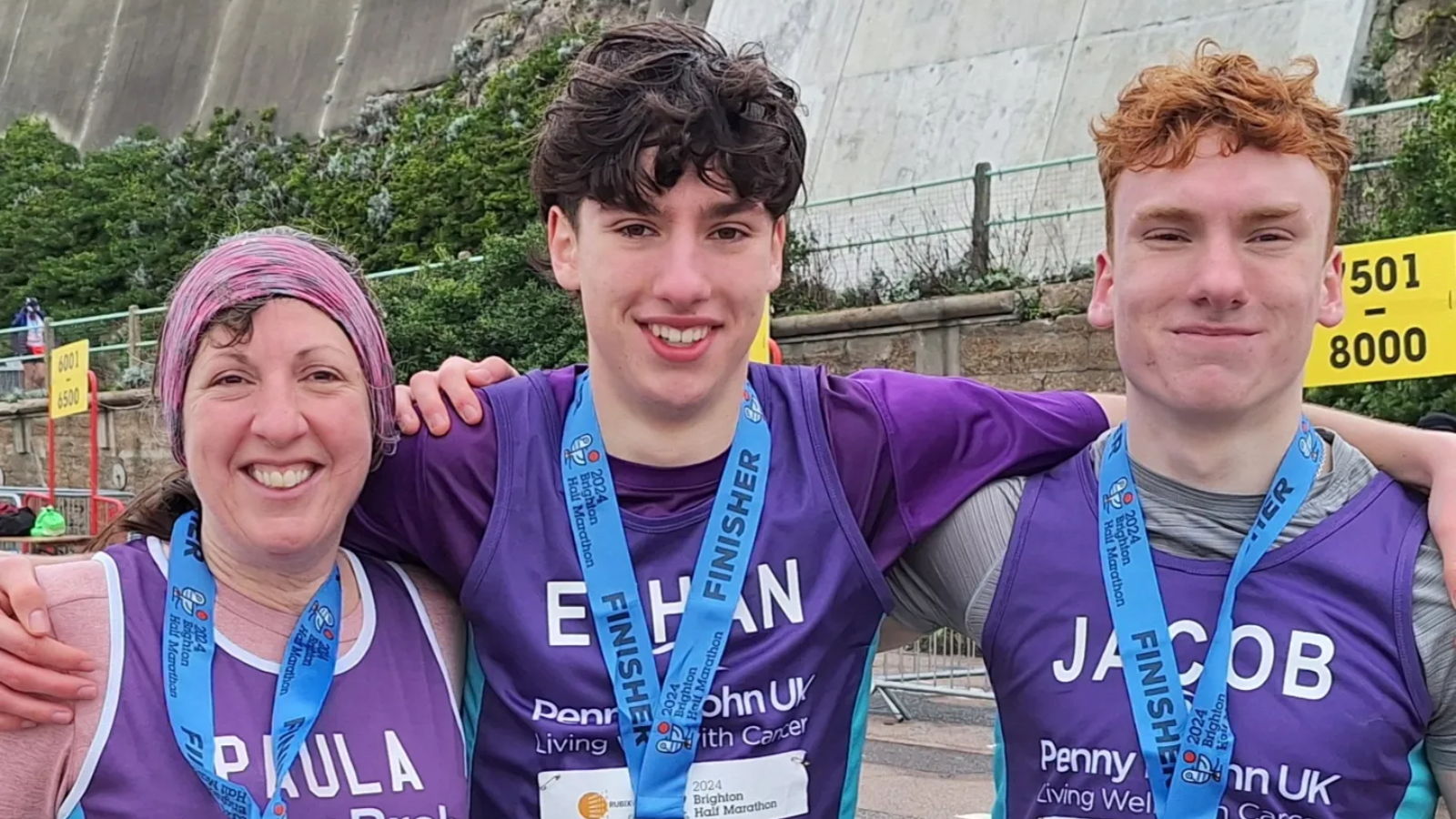 Photo of a woman and two young boys with arms around each other smiling wearing medals after running the Brighton Half Marathon.