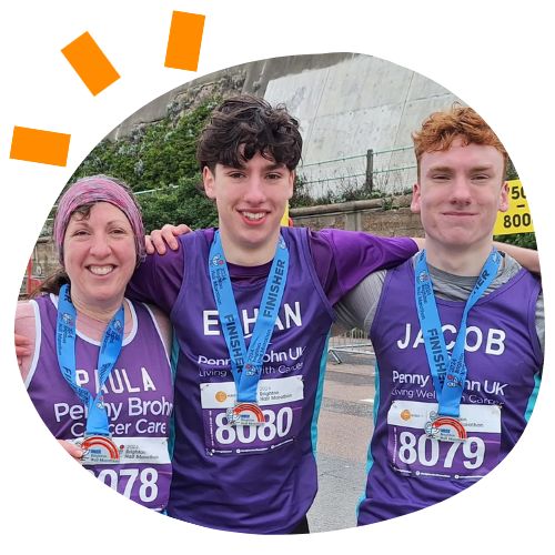 Photo of a woman and two young boys with arms around each other smiling wearing medals after running the Brighton Half Marathon.