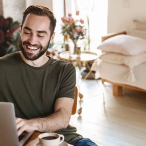 A man sat at his laptop smiling