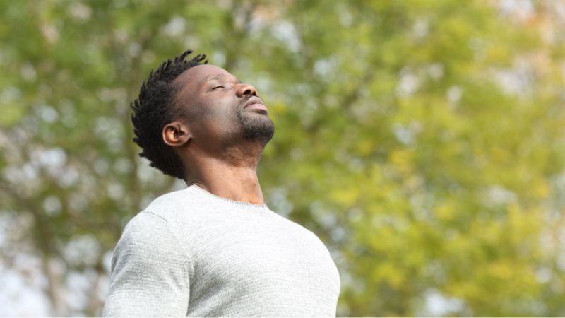 A man standing outdoors breathing slowly