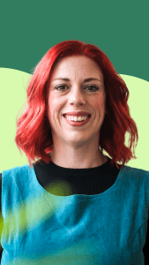 A photo of our Trustee Emma. She has red hair, a blue dress and is smiling for the photo