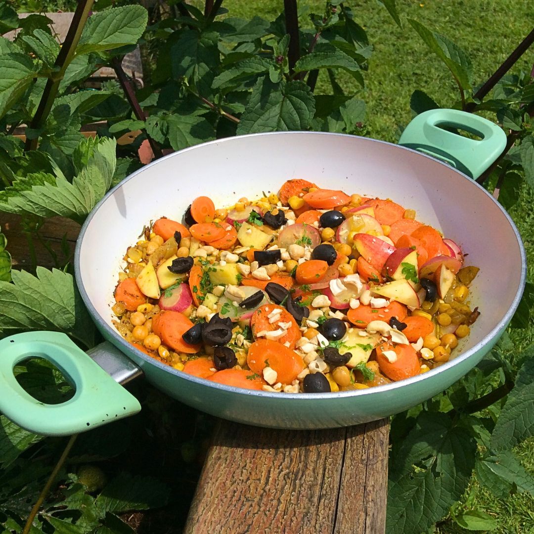 A frying pan in a garden with a Carrot tagine style salad in