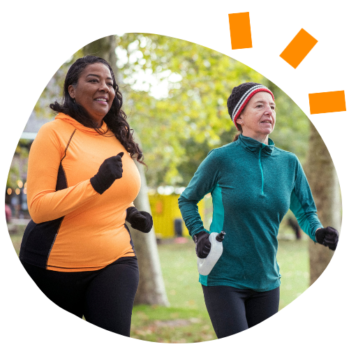 Photo of two women, one black and one caucasian, running in a park.