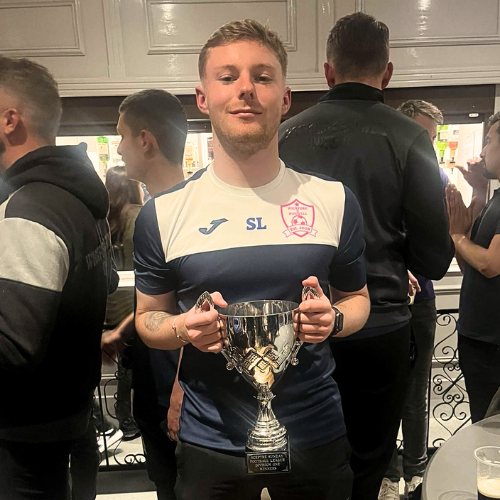 A photo of Shay Lundy holding a football trophy.