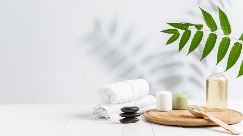 Some towels, candles, oils, and a plant on a table